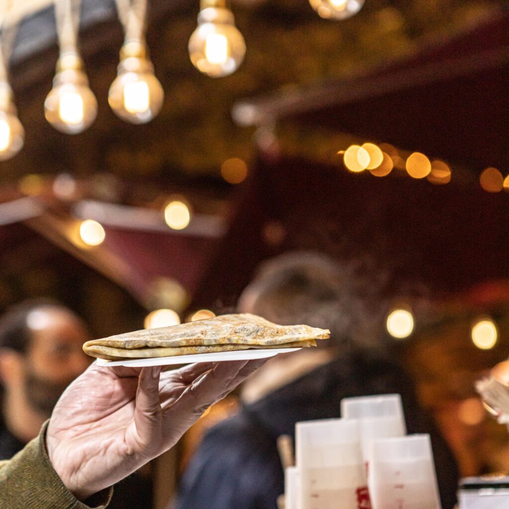 Crêpe chaude et gourmande servie au marché de Noël de Bordeaux, avec une garniture fondante et un cadre festif.