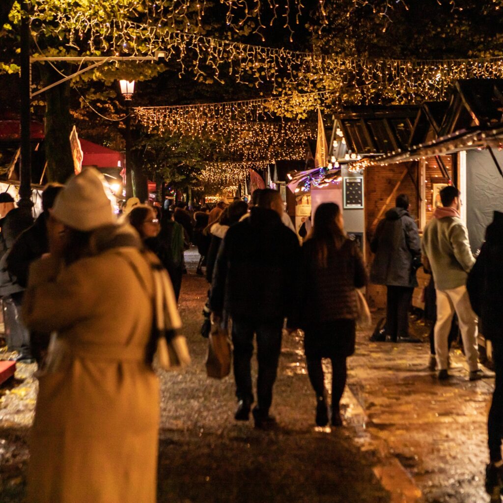 Marché de Noël à Bordeaux la nuit, avec des stands illuminés, des décorations festives et une ambiance chaleureuse sous les lumières scintillantes.